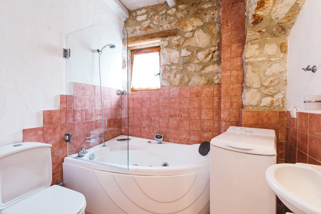 Bathroom with pink tiles and stone walls in Orfos villa Yria