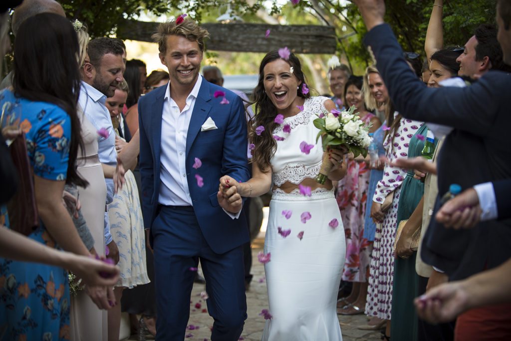 Bride and groom walk down are welcomed by guests with confetti