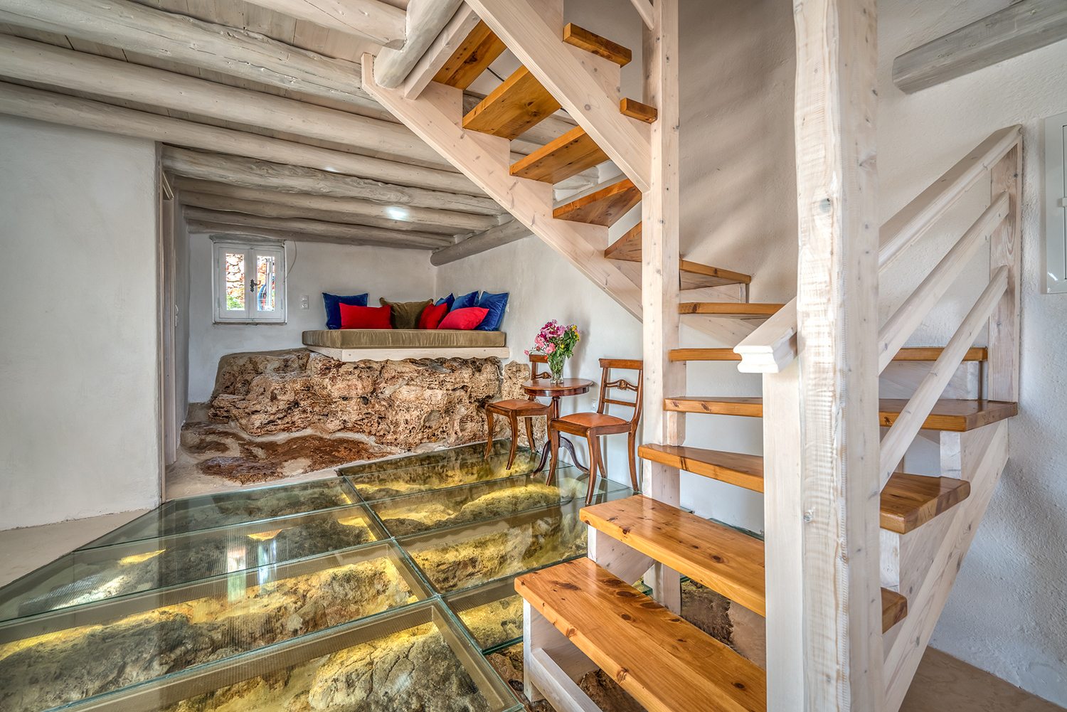 Traditional stone greek villa for 6 people in Zakynthos with blue wooden shutters and plants in terracotta pots staircase and glass floor exposing rocks below