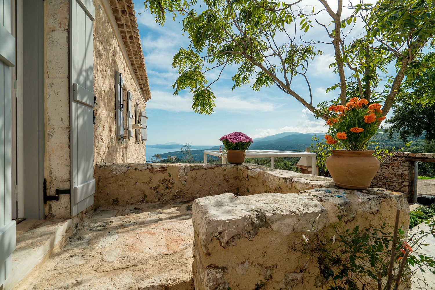 Traditional stone greek villa for 6 people in Zakynthos with blue wooden shutters and plants in terracotta pots