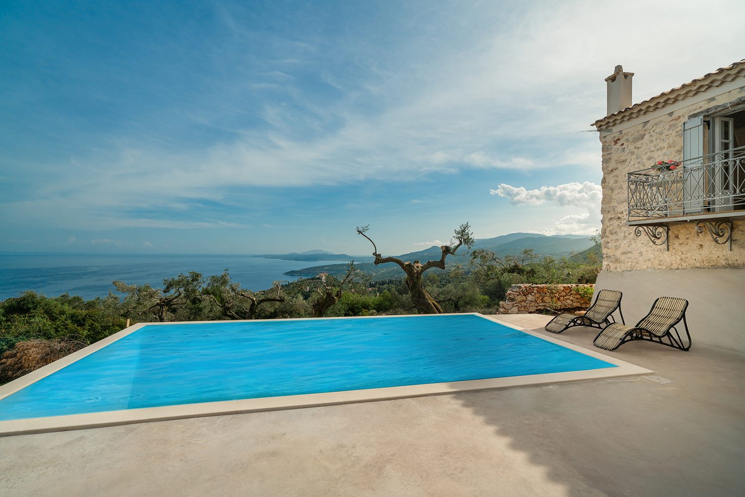 Traditional stone greek villa for 6 people in Zakynthos with blue wooden shutters and plants in terracotta pots