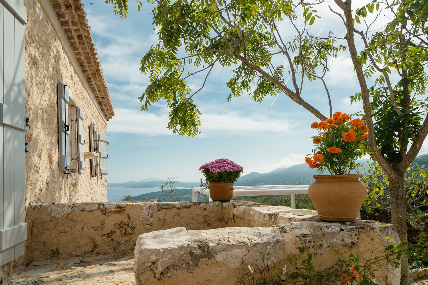 Traditional stone greek villa for 6 people in Zakynthos with blue wooden shutters and plants in terracotta pots