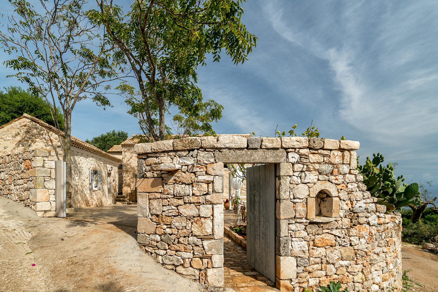 Traditional stone greek villa for 6 people in Zakynthos with blue wooden shutters and plants in terracotta pots