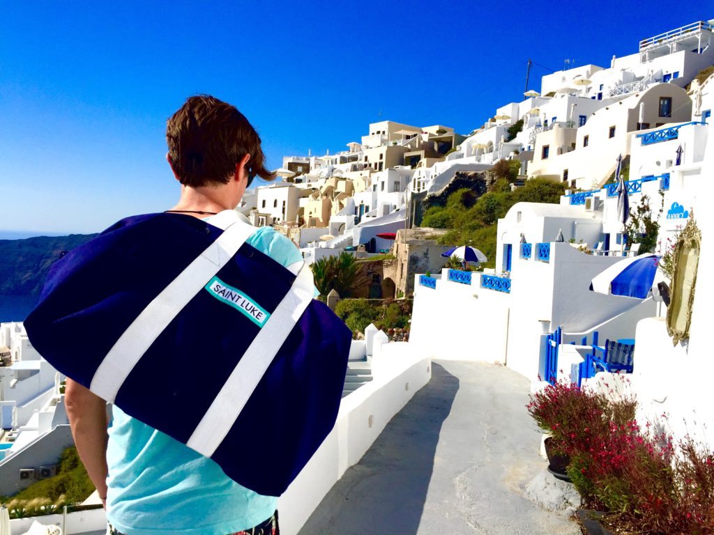 Man in Santorini Greece carrying a large blue holdall over his shoulder