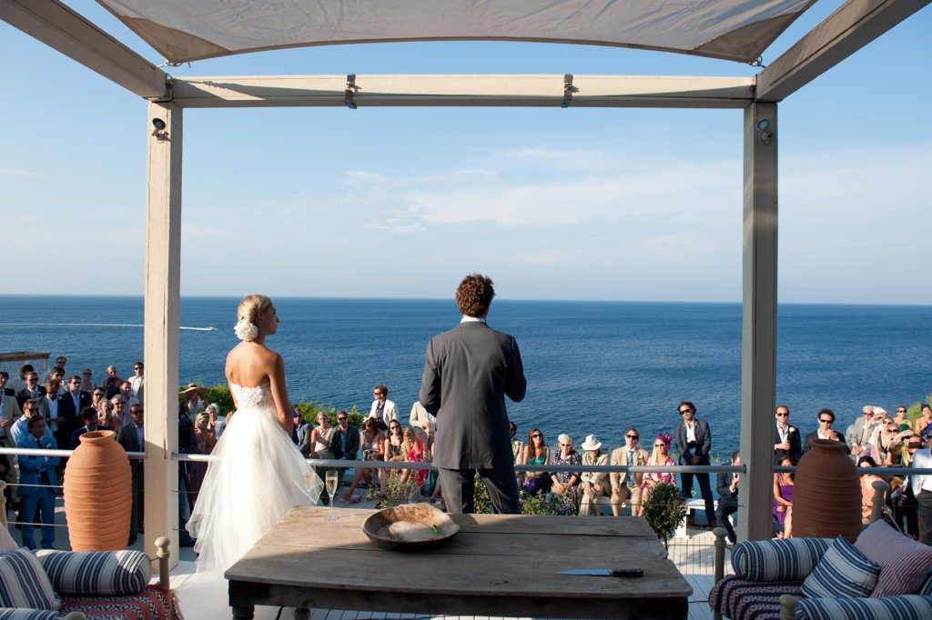 A bride groom stand on the terrace of luxury villa Figari with sea view, a perfect Location by the sea for a wedding in Greece