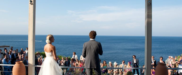 A bride groom stand on the terrace of luxury villa Figari with sea view, a perfect Location by the sea for a wedding in Greece
