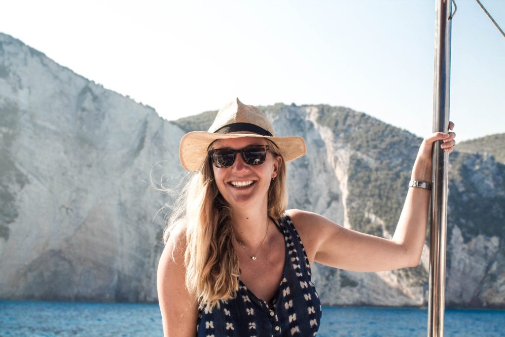 Styish woman with blonde hair and a panama hat on a vintage wooden yacht on the Ionian Sea