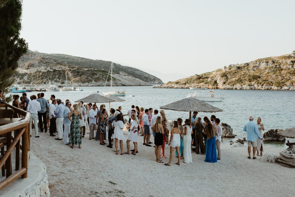 Stylish guests mingle for drinks on a private beach
